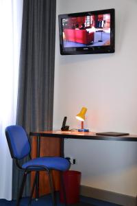 a room with a desk and a tv on the wall at Logis Hotel de Paris in Saint-Avold