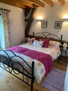 a bedroom with a large bed with purple comforter at Les Gites de Montinazeau - 3 adjoining gites set in quiet and beautiful countryside with free Wi-Fi in Chéniers