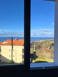 uma janela com vista para um edifício e para o oceano em Suset Star II With Sea View na Calheta