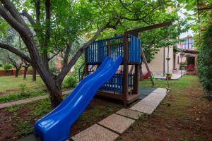 un parque infantil con un tobogán azul junto a un árbol en Apartments Mirella en Novigrad Istria