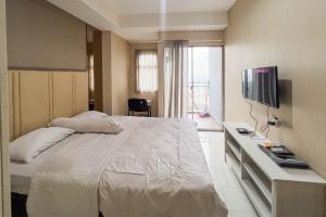 a bedroom with a large bed and a television at RedLiving Springwood Residence - Living space in Warungmangga