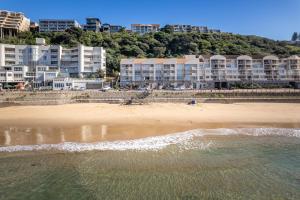 a beach with buildings in the background and the ocean at Cozumel 206 in Umdloti