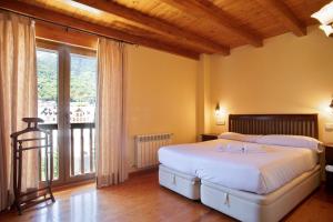 1 dormitorio con cama y ventana grande en Luderna - Apartamento Dera Pincèla, en Vielha
