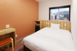 1 dormitorio con cama blanca y ventana en Sasebo Green Hotel, en Sasebo