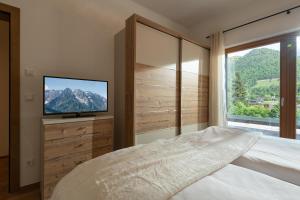 um quarto com uma cama, uma televisão e uma janela em Penthouse Bergseetraum mit 102 qm Dachterrasse em Walchsee