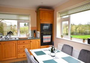 a kitchen with a table and two windows at Rydon Ball in Abbotskerswell