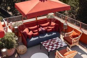 a couch on a patio with a table and an umbrella at La Roqqa in Porto Ercole