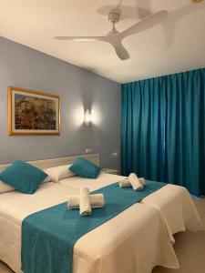 2 camas en una habitación con cortinas azules en Hostal Ferrer, en San Antonio