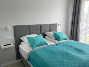 łóżko z dwoma niebieskimi poduszkami na górze w obiekcie Apartament AQUA MAZURY w mieście Ełk