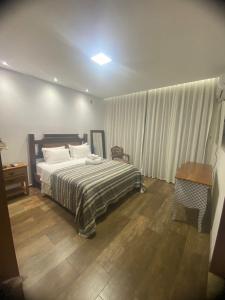 een slaapkamer met een bed en een houten vloer bij Pousada Canto da Seriema in Tiradentes