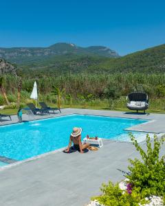 a person sitting next to a swimming pool at NEO Dalyan Residences - Villa 1 in Ortaca