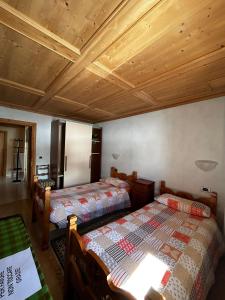 a bedroom with two beds and a wooden ceiling at CASA ARNEIRA in Livigno