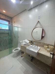 een badkamer met een wastafel, een toilet en een spiegel bij Pousada Canto da Seriema in Tiradentes