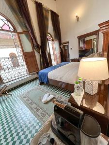 Le Riad Palais d'hotes Suites & Spa Fes في فاس: غرفة نوم بسرير وطاولة مع مصباح
