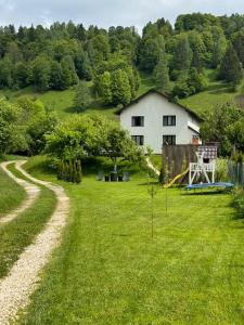 une cour herbeuse avec une maison et une aire de jeux dans l'établissement RDT Guest House-Rai din Transilvania, à Moieciu de Jos