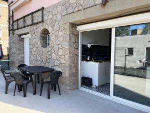 een patio met een tafel en stoelen naast een stenen muur bij Appartement proche CHU in Saint-Priest-en-Jarez