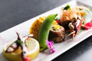 a plate of food with meat and vegetables on a table at Dogo Onsen Yachiyo 道後温泉八千代 in Matsuyama