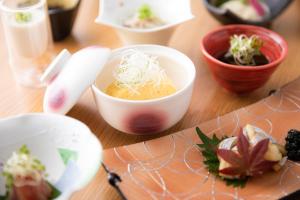a table with bowls and plates of food on it at Dogo Onsen Yachiyo 道後温泉八千代 in Matsuyama