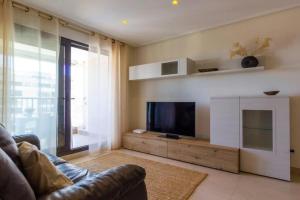 sala de estar con sofá y TV de pantalla plana en Alboraya Apartamento con vista al mar y piscina en Valencia