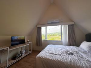 a bedroom with a bed and a tv and a window at Bintang Langit Lodge Ciater in Cicadas