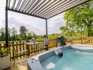 a hot tub on a patio with a table and chairs at The Wood Shed, Bank Top Farm in Ashbourne