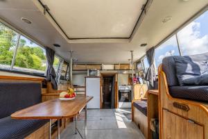 a kitchen and dining area in a van with a wooden table at Péniche - Nuits insolites in Nort-sur-Erdre