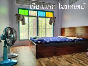 Schlafzimmer mit einem Bett, einem Ventilator und einem Fenster in der Unterkunft เรือนแรก โฮมสเตย์ in Ban Tha Sao