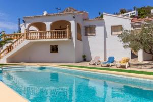 a villa with a swimming pool in front of a house at Chalet Los Olivos con piscina in Jávea