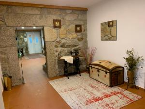 a room with a stone wall with a table and a chest at Casa das Hortênsias in Cerdeira