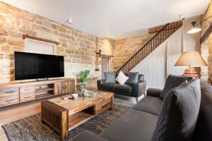 uma sala de estar com uma televisão, um sofá e uma mesa em Iconic Luxury 5BR Home w/ Opera and Harbour view em Sidney