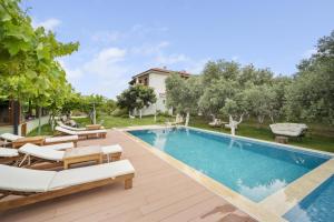 einen Pool mit Liegestühlen und ein Haus in der Unterkunft GRAPE DATÇA in Kızlanköy