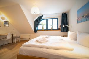 a bedroom with a white bed with a desk and a window at Reetdachhaus Holunder 2 in Puddemin