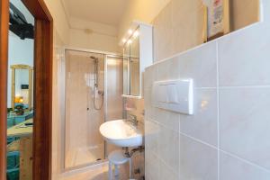 uma casa de banho branca com um lavatório e um chuveiro em Hotel Castel Mani em San Lorenzo in Banale