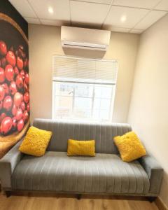 un sofá gris con 2 almohadas amarillas en una habitación en Peper Korrel en Paarl