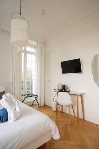 Habitación blanca con escritorio y cama en Les Garennes - Hôtel Spa Bénodet en Bénodet