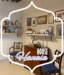 a room with a table and chairs and a house malanca sign at Hanaia House in Stone Town