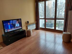 a living room with a flat screen tv and a wooden floor at T3 77 m2 calme+parking proche Paris & métro in Vanves