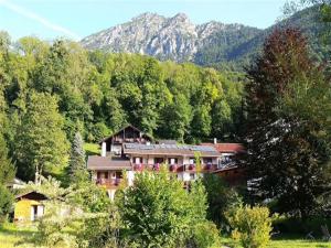 a house in the middle of a forest with mountains at Ferienwohnungen Quellenhof in Bad Reichenhall