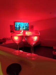 two wine glasses sitting on a bar in a red room at Ile des Plaisirs - Domaine de Charme et table d'hôtes Caraïbéenne in Graulhet
