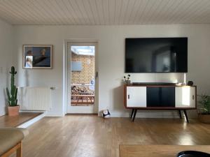 a living room with a large flat screen tv on a wall at Bolig med sommerhusvibes, 80 meter fra badesø in Silkeborg