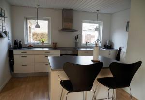 a kitchen with two black chairs and a counter at Bolig med sommerhusvibes, 80 meter fra badesø in Silkeborg