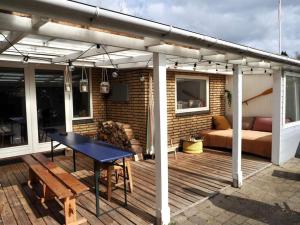 a patio with a table and a couch on a deck at Bolig med sommerhusvibes, 80 meter fra badesø in Silkeborg