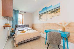 a bedroom with a bed and a blue desk at Apartamenty NCNK Baltic Park MEDIUM w Stegnie - 500 m do plaży in Stegna