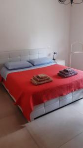 um quarto com uma cama vermelha com duas toalhas em Casa di campagna pace e tranquillità em Brentanella