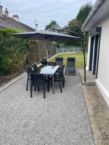 a patio with a table and chairs under an umbrella at Maison plain pied a Dieppe in Dieppe