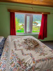 1 dormitorio con 1 cama y una ventana con cortinas rojas en Friends guest house en Pahalgām