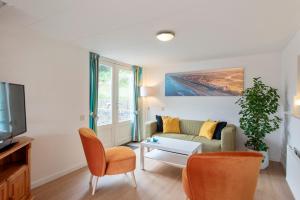 een woonkamer met een bank en een tv bij Anne's Huisje with private parking in Zandvoort