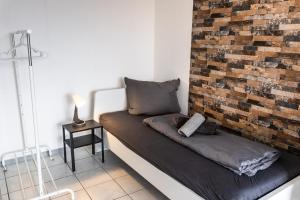 a room with a couch against a brick wall at CosyHomes24 - Apartment with balcony and parking space - WIT01 in Witten