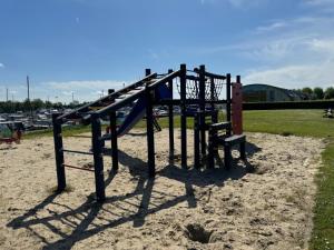 a playground with a slide and a bench in the sand at Hausboot KOMET Luxus und Natur pur max 6 Pers in Lathum