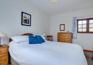 ein Schlafzimmer mit einem großen weißen Bett mit blauen Kissen in der Unterkunft Shippon in Walton West